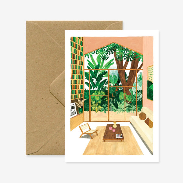 A greeting card with an illustration of a room with large windows and indoor plants, accompanied by a brown envelope.