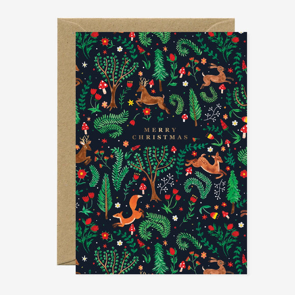 A Christmas greeting card featuring an illustration of a forest scene with deer, trees, and festive decorations, and the text 'Merry Christmas' in gold foil.