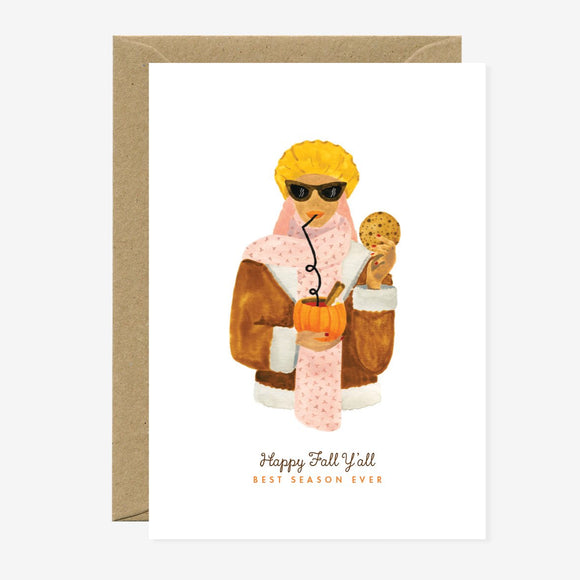 A greeting card with an illustration of a character in autumn clothing holding a pumpkin and a coffee cup, with text 'Happy Fall Y'all'. It comes with a brown envelope.