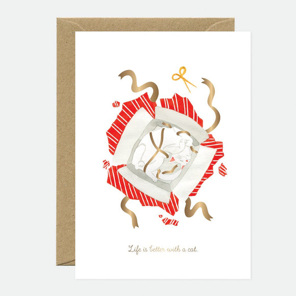 Greeting card with an illustration of a cat wrapped in a gift bow, with gold foil details and a brown envelope.