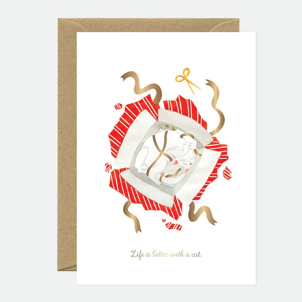 Greeting card with an illustration of a cat wrapped in a gift bow, with gold foil details and a brown envelope.