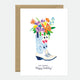 A birthday greeting card with a floral design in a boot, with a 'Happy Birthday' text, presented with a brown envelope.