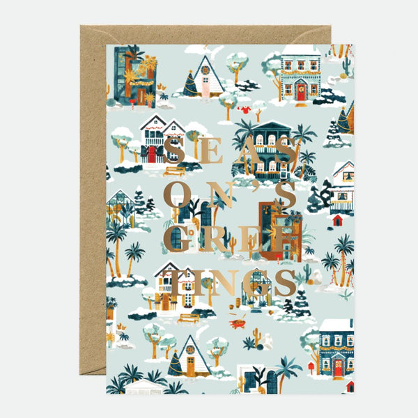 A Christmas greeting card featuring a gold foil design with houses, trees, and the text 'This is a great year' on a light background, accompanied by a brown envelope.