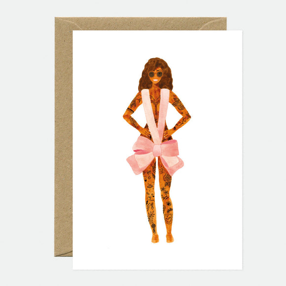 A greeting card featuring an illustration of a woman with a pink bow tie and brown hair, accompanied by a brown envelope.