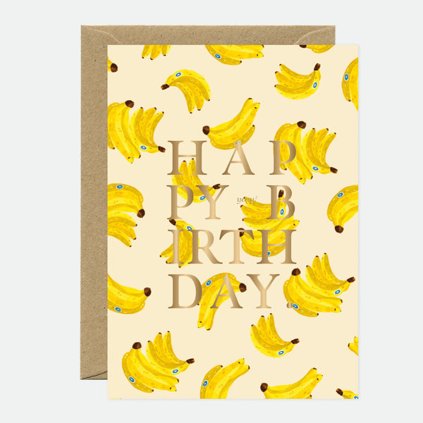 A birthday greeting card with a pattern of bananas and the words 'HAPPY BIRTHDAY' in gold foil on the front.