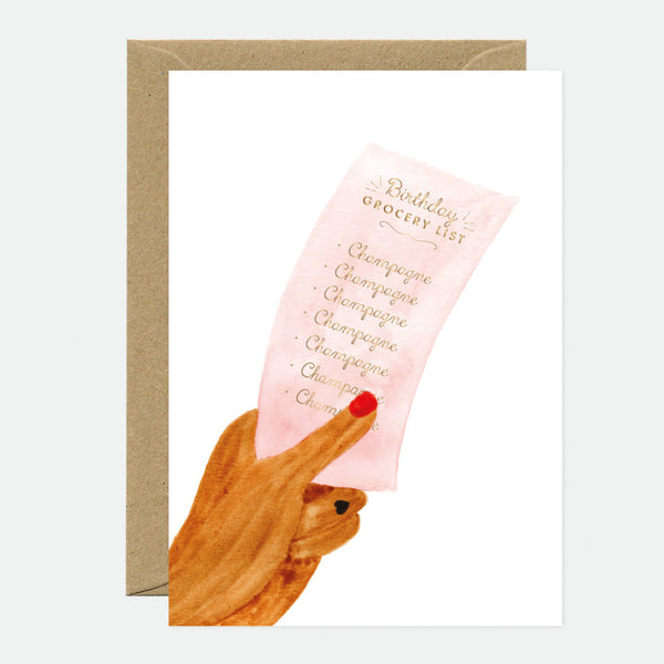 A greeting card with a illustration of a hand holding a card with the text 'Birthday grocery list' in gold foil, accompanied by a brown envelope.