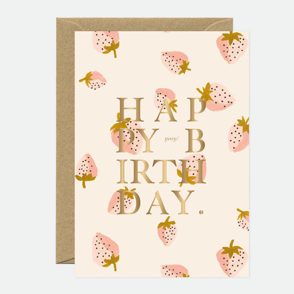 A greeting card with gold foil text saying 'HAPPY BIRTHDAY' and decorated with gold foil strawberry patterns.