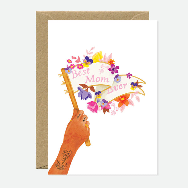 Greeting card with an illustration of a hand holding a banner that reads 'Best Mom Ever' with floral elements and a space for a personalized message.