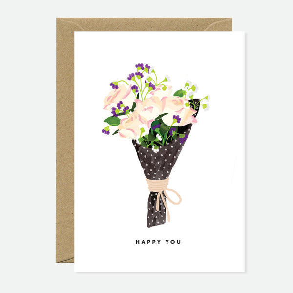 A greeting card with a bouquet of pink roses illustration, accompanied by a brown envelope. The card has the text 'HAPPY YOU' on it.