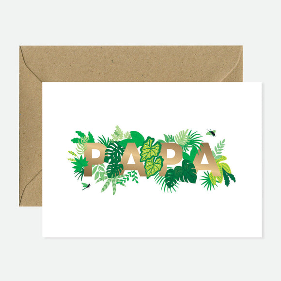 A greeting card with 'PAPA' written in gold foil surrounded by green leaf illustrations, accompanied by a brown envelope.