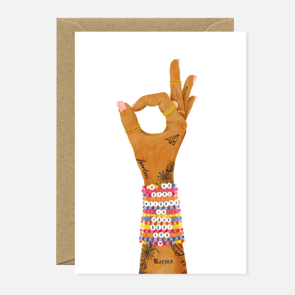 Greeting card with an illustration of a tattooed hand making an “OK” gesture, wearing colorful beaded bracelets spelling an uplifting message.