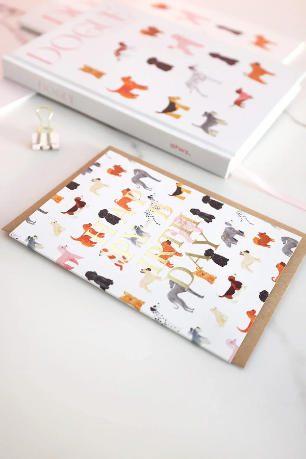 Birthday card with multicolored dog pattern and gold foil “Happy Birthday” text, styled with matching Dogue notebooks.