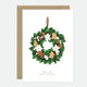 Greeting card with an elegant Christmas wreath decorated with pinecones, gingerbread cookies, dried oranges, and white flowers, with gold foil accents.