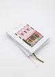 Stack of Daily bakery notebooks with illustrated pink storefront cover and ribbon bookmarks in pink and green.