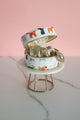Open round jewelry box with dog pattern, showing interior storage and golden jewelry pieces