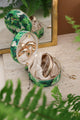 Green tropical jewelry box with leafy pattern, shown open with gold jewelry inside