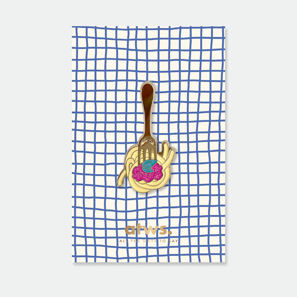 Fork and Pasta enamel pin by All the Ways to Say featuring gold-plated fork twirling spaghetti with red sauce on blue checkered background.