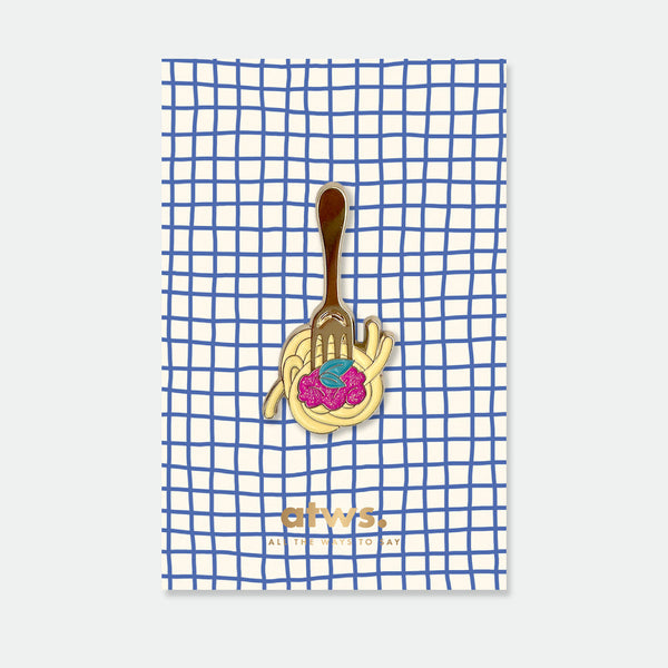 Fork and Pasta enamel pin by All the Ways to Say featuring gold-plated fork twirling spaghetti with red sauce on blue checkered background.