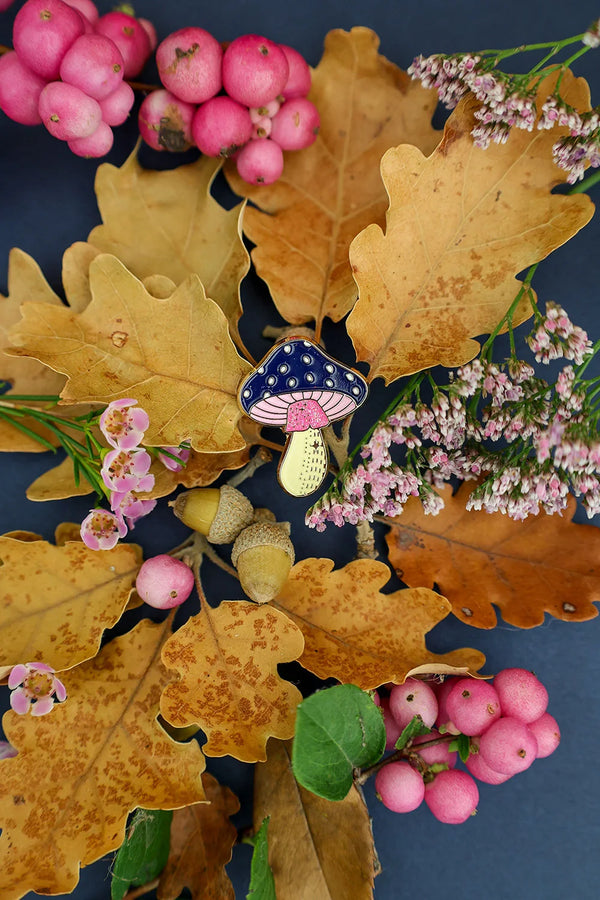 Crazy Mushroom enamel pin by All The Ways To Say surrounded by dry oak leaves, berries, and small flowers – autumn mood