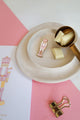 Pink Nutcracker enamel pin by All The Ways To Say on pink and white background – cozy Christmas mood with chocolate and gold details