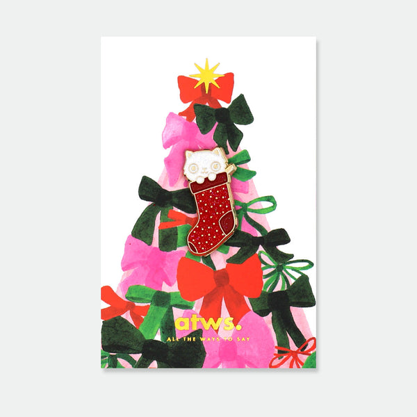 Cat Sock enamel pin by All the Ways to Say featuring white cat inside red glittery Christmas stocking with gold-plated details on festive bow background.