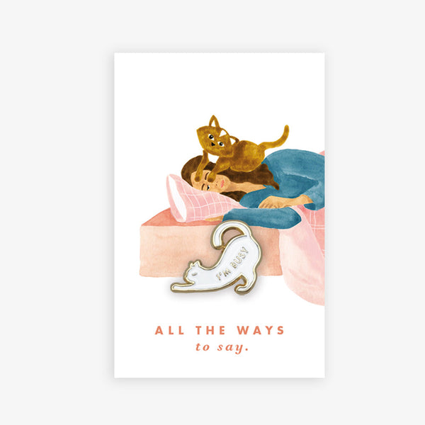 Busy Cat enamel pin by All the Ways to Say featuring white cat with gold-plated outline and “I’m busy” engraving on cozy bed illustration with cats.