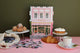 Pink Bakery puzzle by All the Ways to Say displayed with pastries and croissant on a pink table — charming Parisian bakery illustration with gold details.