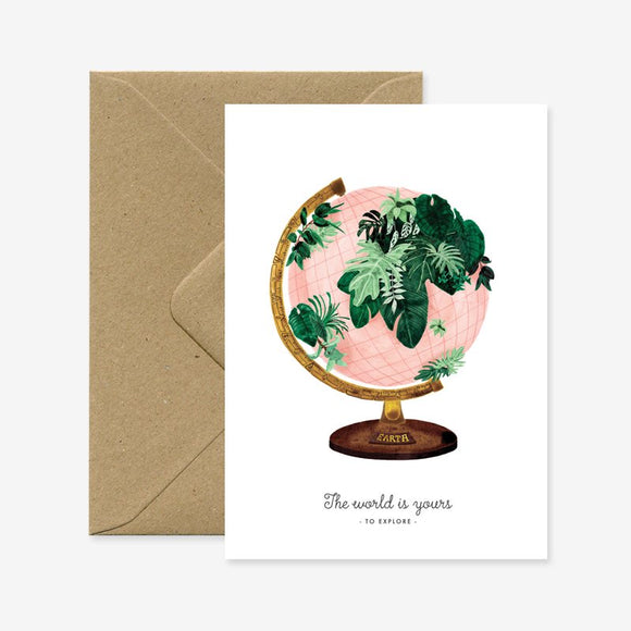 Greeting card with a drawing of the world map surrounded by green leaves on a pink background, paired with a recycled brown envelope.