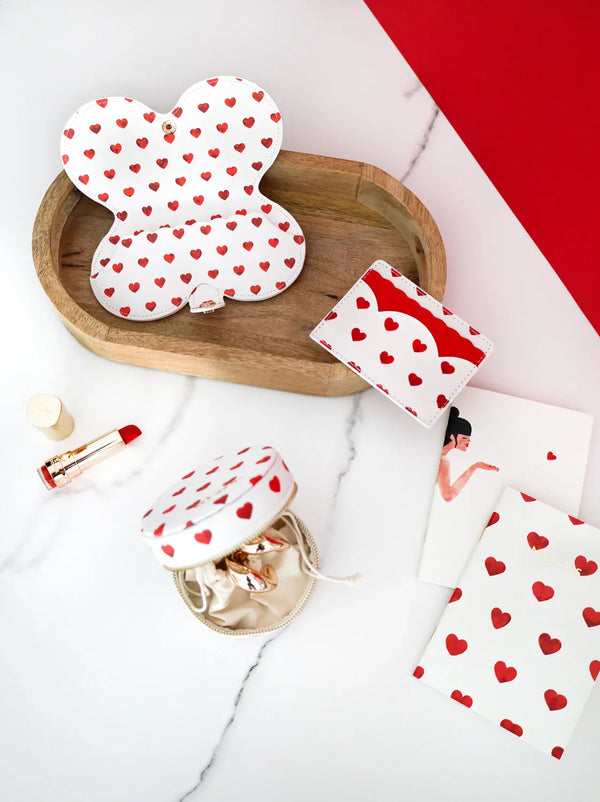 Open Red Hearts glasses case showing red hearts pattern, with matching card holder and jewelry case, styled with lipstick.