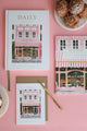 Flat lay of The Baguetter stationery collection featuring notebooks, card and coffee cup on a pink background