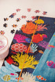 Boarding Soon jigsaw puzzle in progress, colorful illustrated coral reef with clownfish and tropical fish, loose pieces and a pink drink