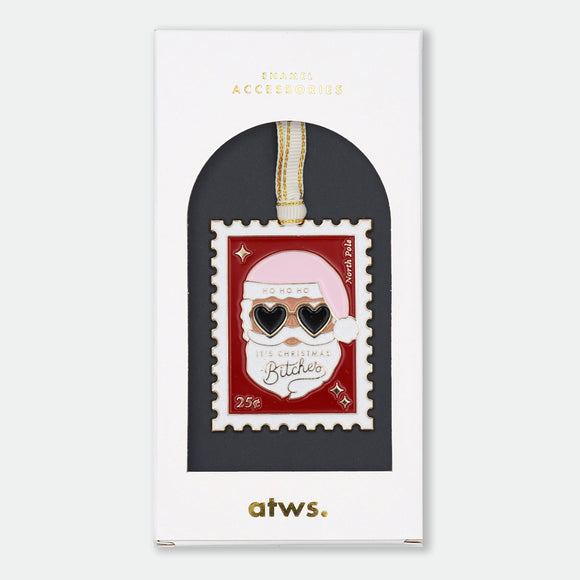 Gold-tone enamel Christmas ornament shaped like a postage stamp featuring Santa Claus wearing heart-shaped sunglasses, text reading "Ho Ho Ho, It's Christmas Bitches," "North Pole," and "25¢"