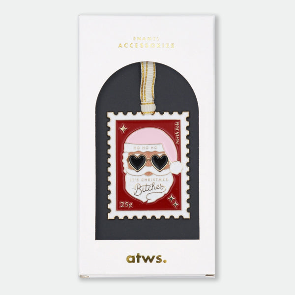 Gold-tone enamel Christmas ornament shaped like a postage stamp featuring Santa Claus wearing heart-shaped sunglasses, text reading "Ho Ho Ho, It's Christmas Bitches," "North Pole," and "25¢"