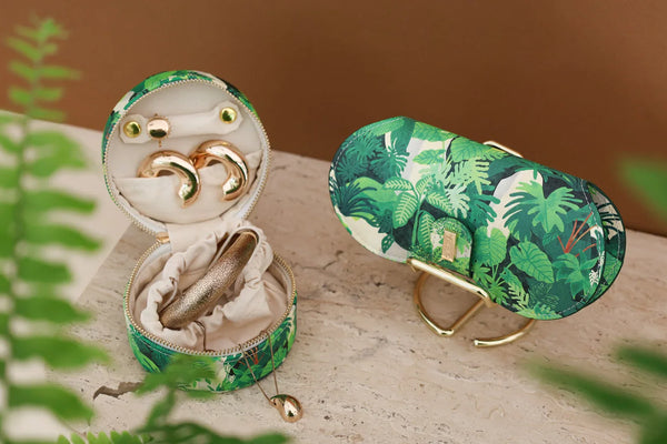 Tropical Green Cliff sunglasses case with matching jewelry case, decorated with lush green leaves pattern, styled with gold accessories.