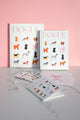 Dogue stationery and accessories styled on marble desk with pink background