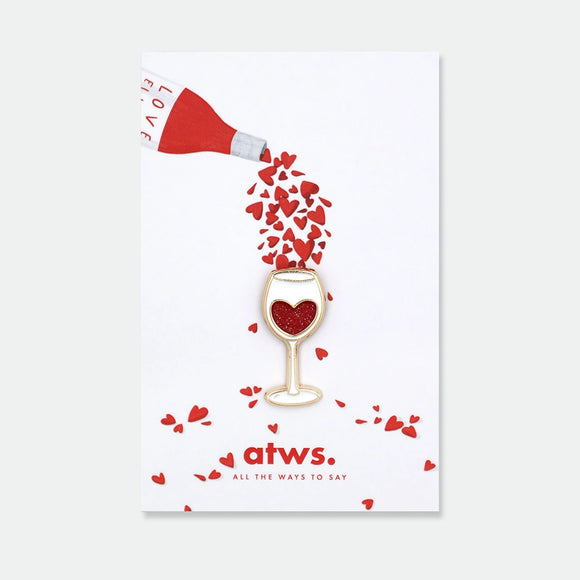 Enamel pin shaped like a wine glass with a red glitter heart inside
