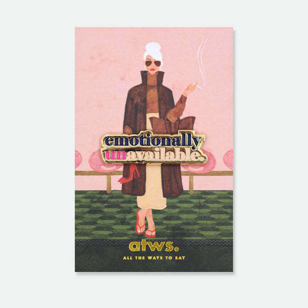 Enamel pin reading "emotionally unavailable" in bold gold and pink lettering