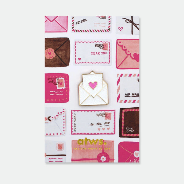 Enamel pin of a white envelope with a glitter pink heart peeking out