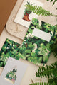 Green Cliff botanical notebooks and stationery with lush jungle leaf patterns, surrounded by ferns.
