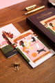 Happy pets Greeting card - Cozy lifestyle illustration featuring dogs and cats on a bed, displayed on a wooden table.