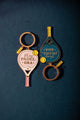 "In my padel era" enamel keychains shaped like padel rackets with a tennis ball, in pink and blue with gold details