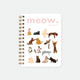 Meow. A5 spiral notebook by All The Ways To Say, white cover styled like a magazine with "meow. Issue No. 01" text and a grid of illustrated cats in various poses, spiral binding visible on the left edge