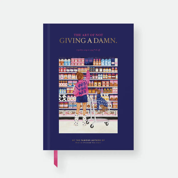 Not Giving A Damn hardcover A5 notebook by All The Ways To Say, navy cover styled like a book jacket with the title "The Art of Not Giving A Damn, a polite way to say f*ck off," a fake author credit, and an illustration of a girl reaching for a shelf item with her dog in a shopping cart