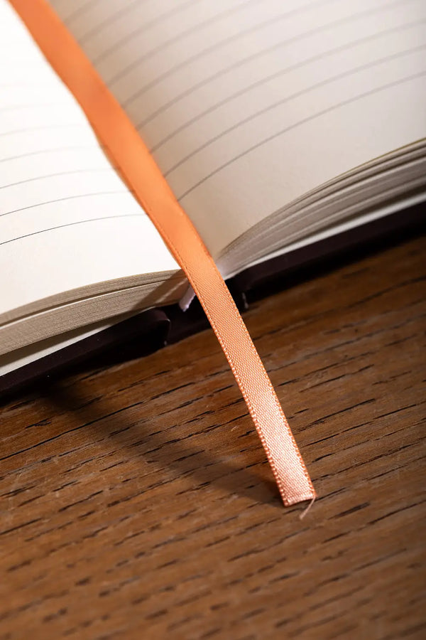 How to be fulfilled Hardcover Notebook A5 - Detail of the orange ribbon bookmark and high-quality binding.