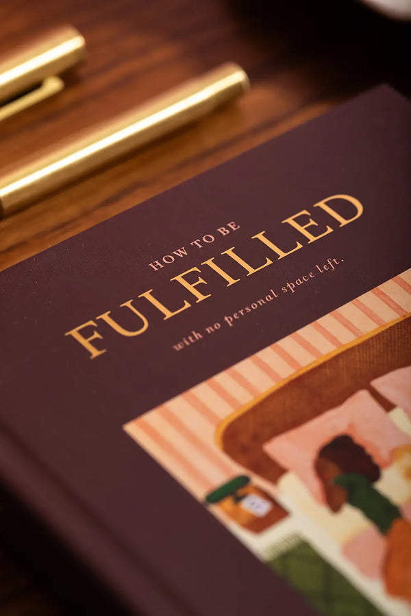 How to be fulfilled Hardcover Notebook A5 - Close-up of the gold foil title and textured burgundy cover.