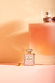 N°1 Bitch - Pins: elegant product shot of the perfume-shaped pin against a warm peach-toned background.
