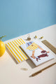 Summer Dachshund Pocket Notebook A6 DUO - High angle view with a lemon and golden office supplies.