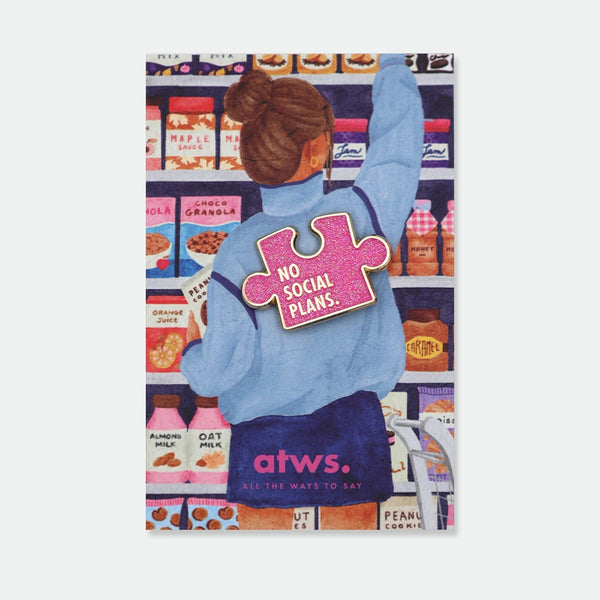 Enamel pin shaped like a glittery pink puzzle piece reading "No social plans," gold outline