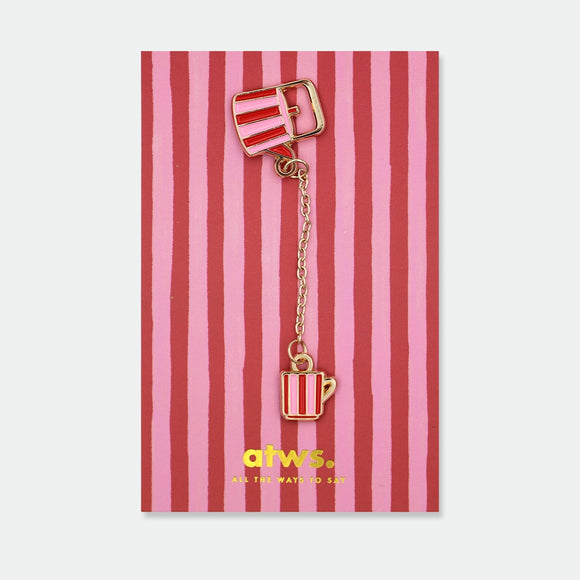Enamel pin of a red and pink striped teapot connected by a gold chain to a matching striped teacup