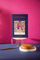 "The art of not giving a damn" A5 hardcover notebook in navy, cover showing a girl in a pink jacket reaching for jam in a grocery aisle